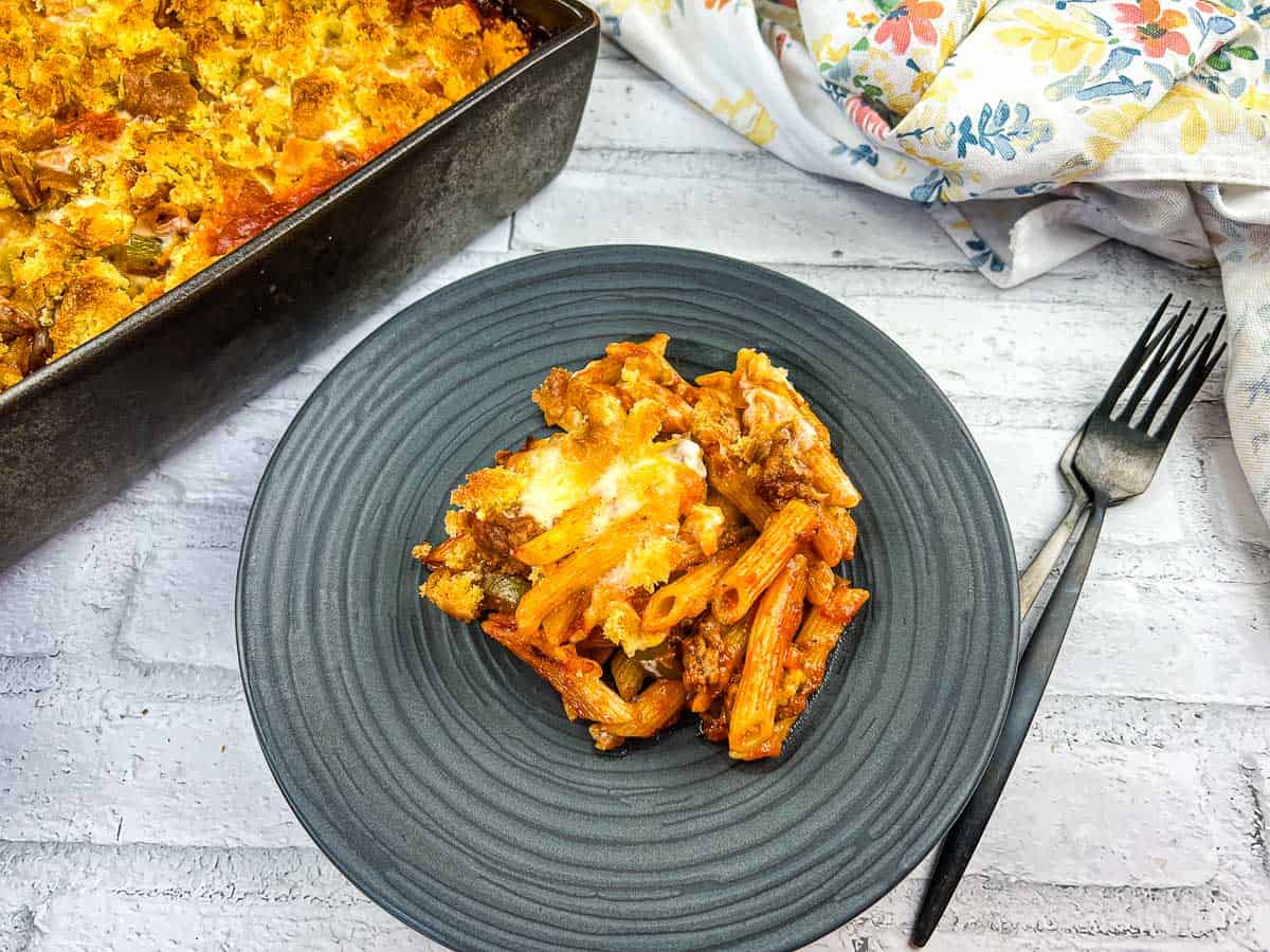 A black plate of Sloppy Joes Casserole with more in the baking dish.