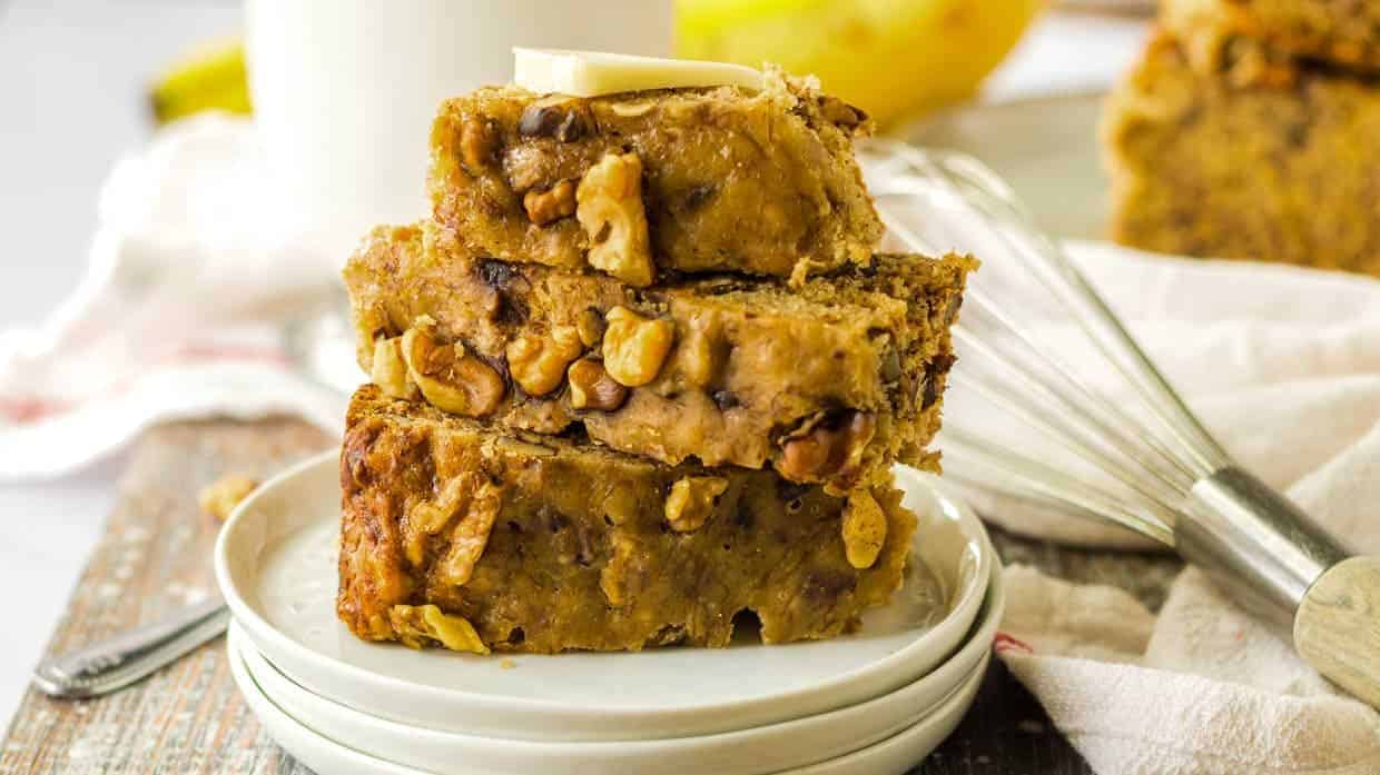 Stack of banana bread on a plate topped with a pat of butter.