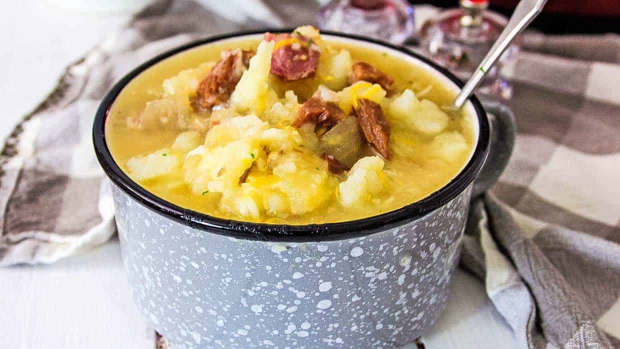 Ham and Potato soup in a gray and white bowl with a spoon.