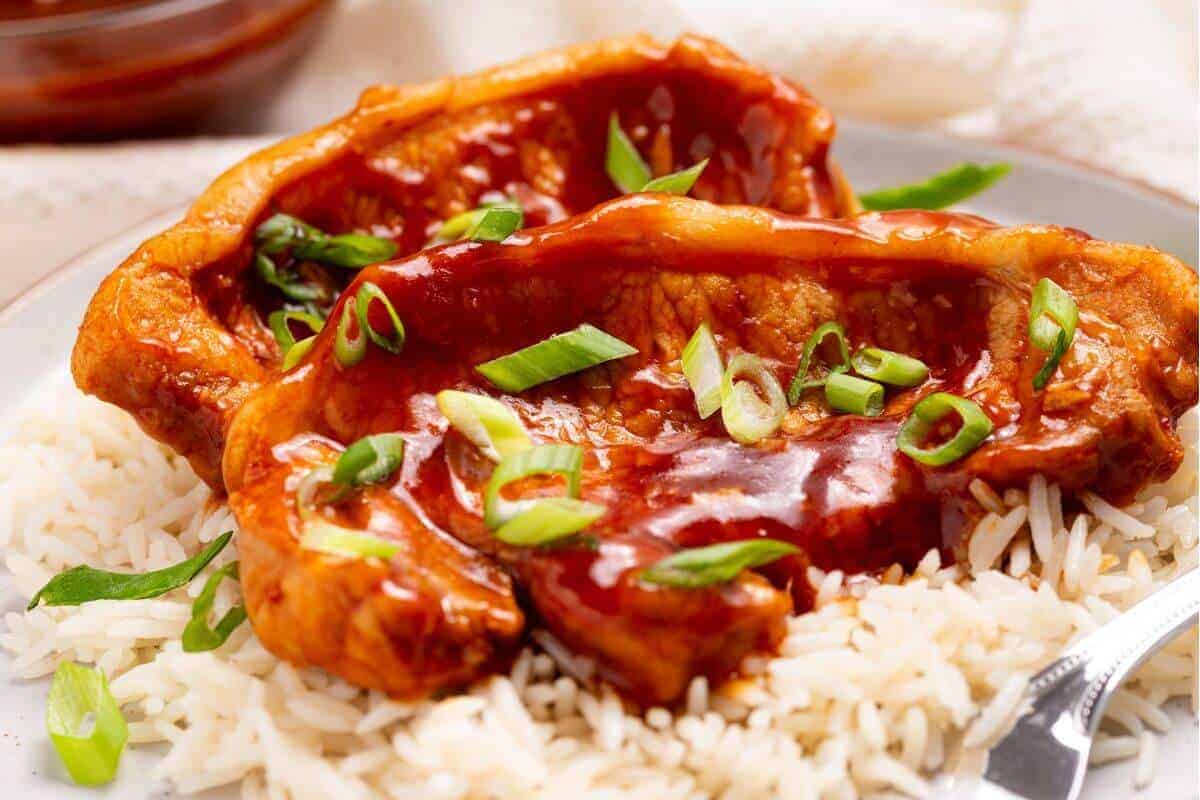 Slow cooker pork chops with rice and sauce on a plate.