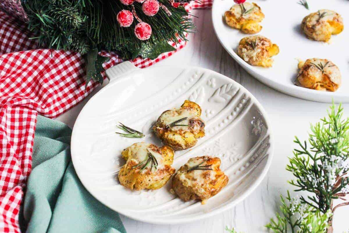 Cheesy smashed potatoes on a plate next to Christmas decor.