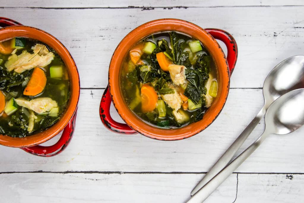 Two bowls of chicken soup on a wooden table.