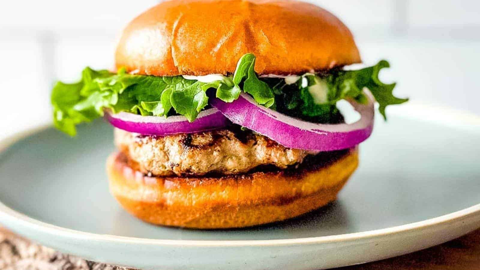 A closeup side view is shown of an air fryer turkey burger on a light blue plate.