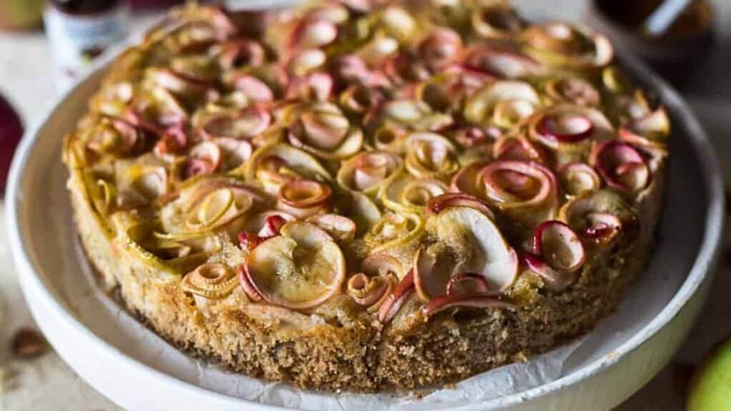 A cake with apples on top of a white plate.