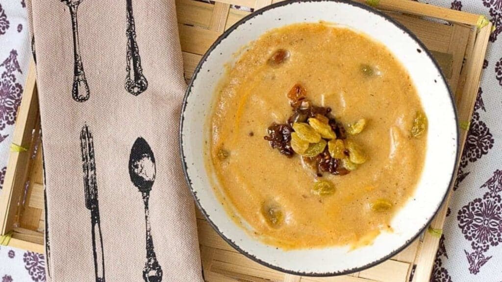 A bowl of soup is sitting on a wooden tray.