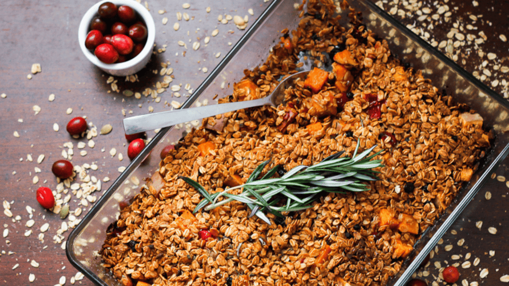 A dish of granola with cranberries and sprigs of rosemary.