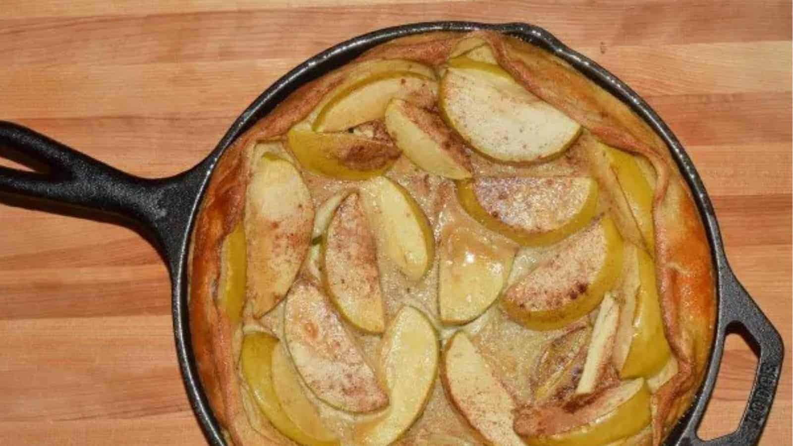 Image shows an overhead shot of an Apple Puff Pancake in a cast iron skillet.