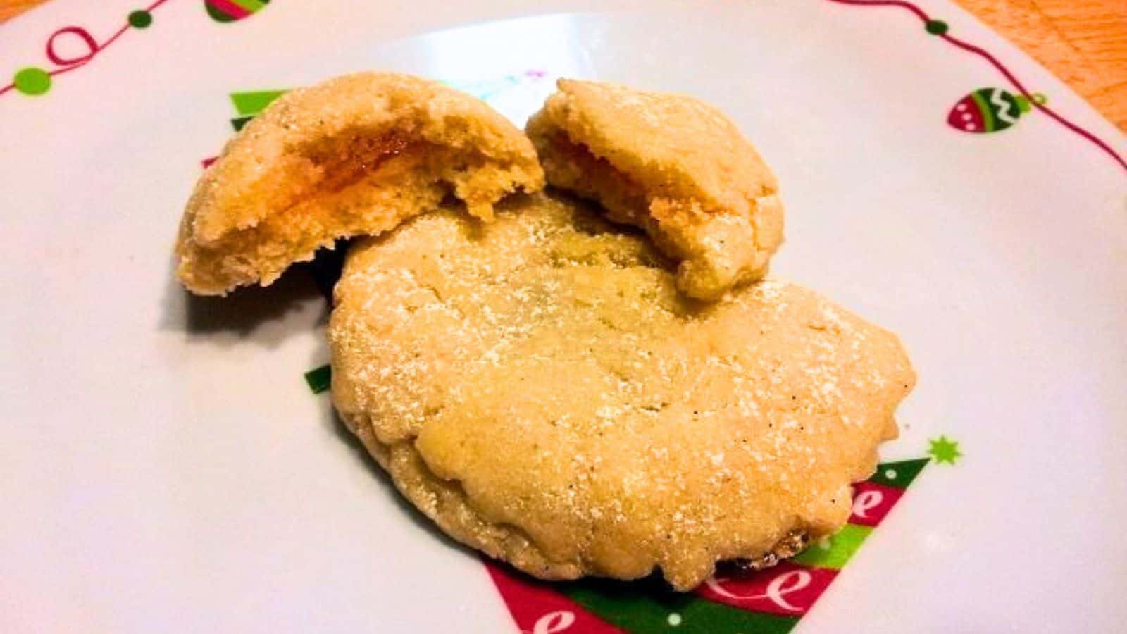 Image shows A plate of apricot crescent cookies with a bite taken out of them.