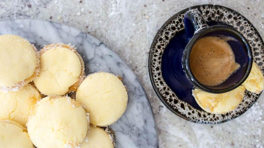 A plate of cookies next to a cup of coffee.