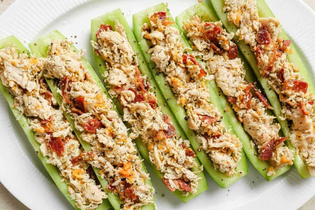 Stuffed cucumber boats with chicken and bacon on a white plate.