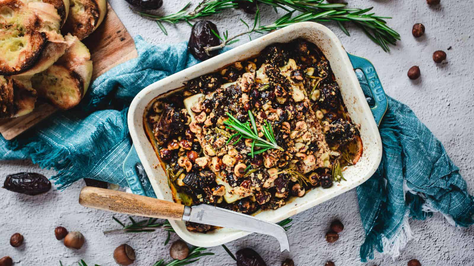 A holiday appetizer dish with figs, nuts and bread on a blue background.