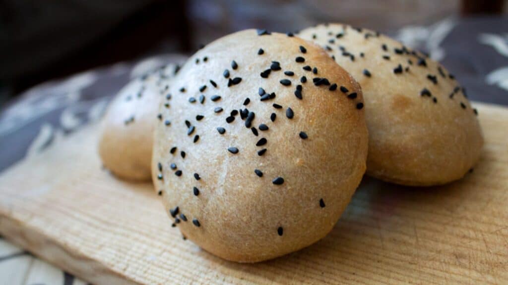 Sesame buns with sesame seeds on a baking sheet.