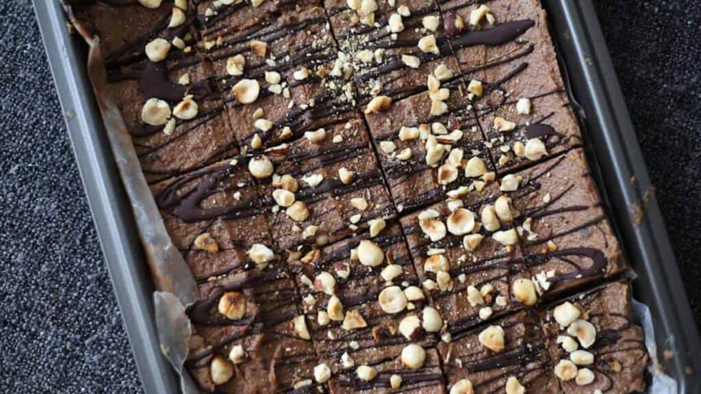 A brownie with chocolate and nuts in a pan.