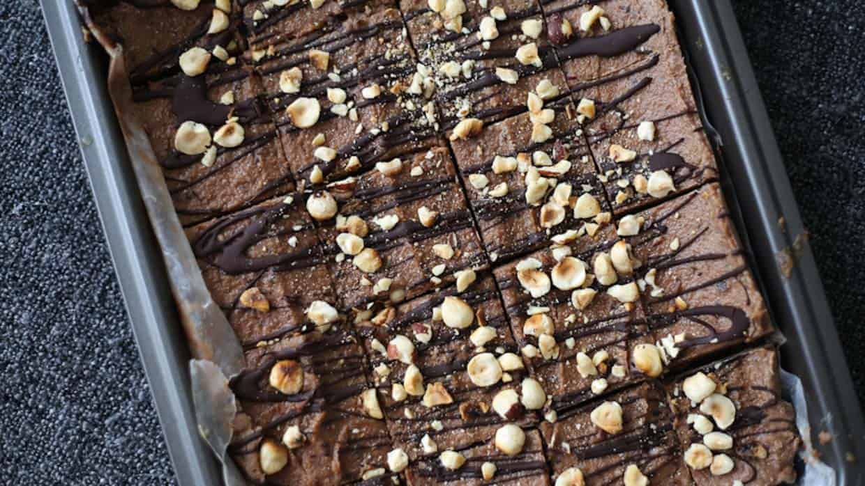 A brownie with chocolate and nuts in a pan.