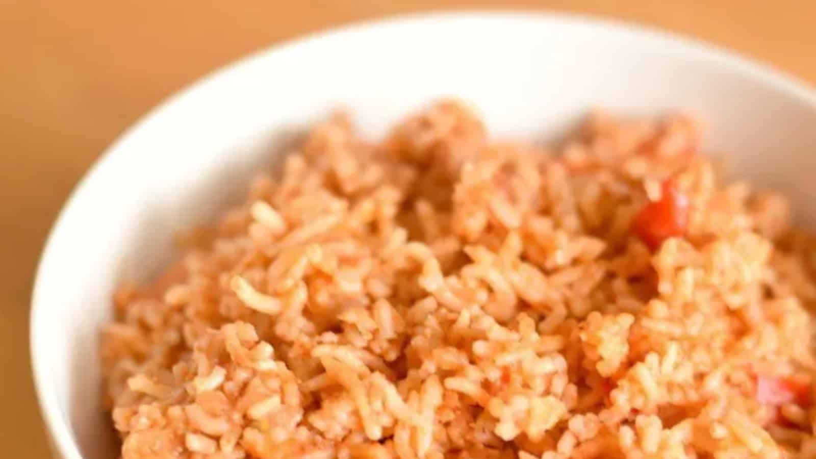 Overhead image of a white bowl containing Spanish rice sitting on a wooden board.