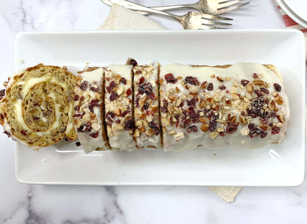 A slice of cranberry cinnamon roll on a white plate.