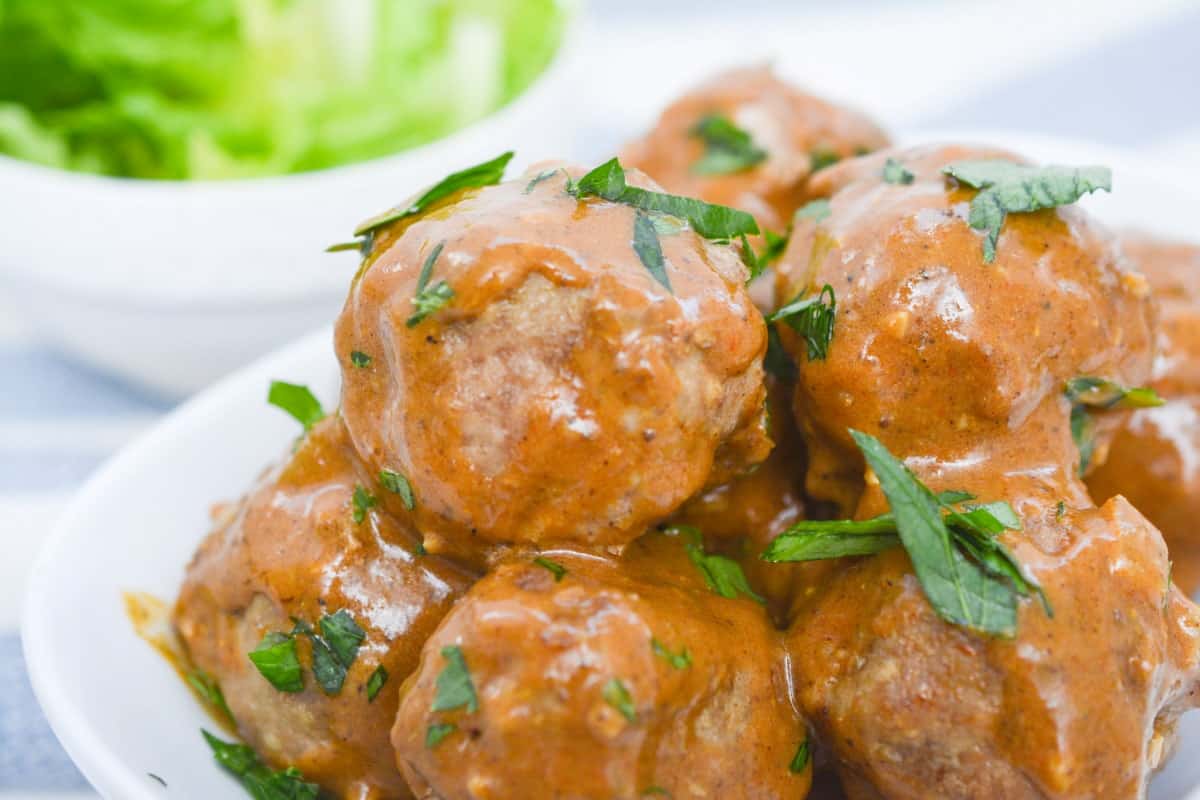 Chicken meatballs in a white bowl with a fork.