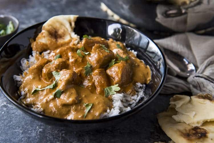 A bowl of chicken tikka masala with basmati rice and naan.