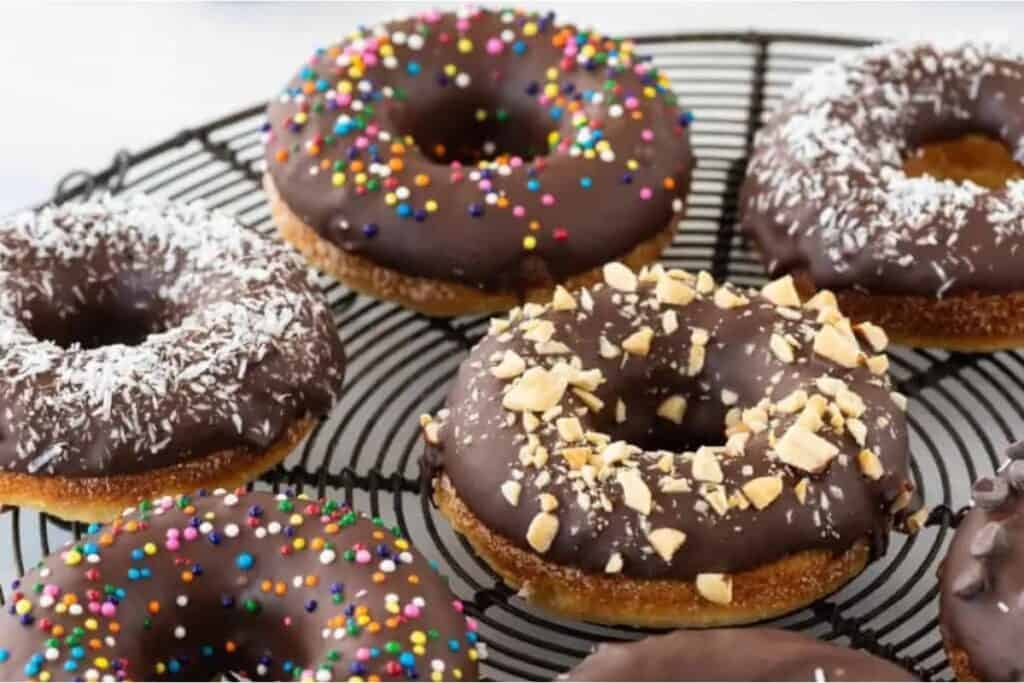 Chocolate donuts on a cooling rack with sprinkles.