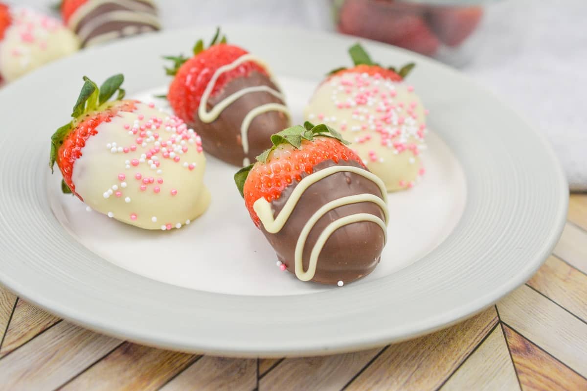 Chocolate covered strawberries on a white plate.