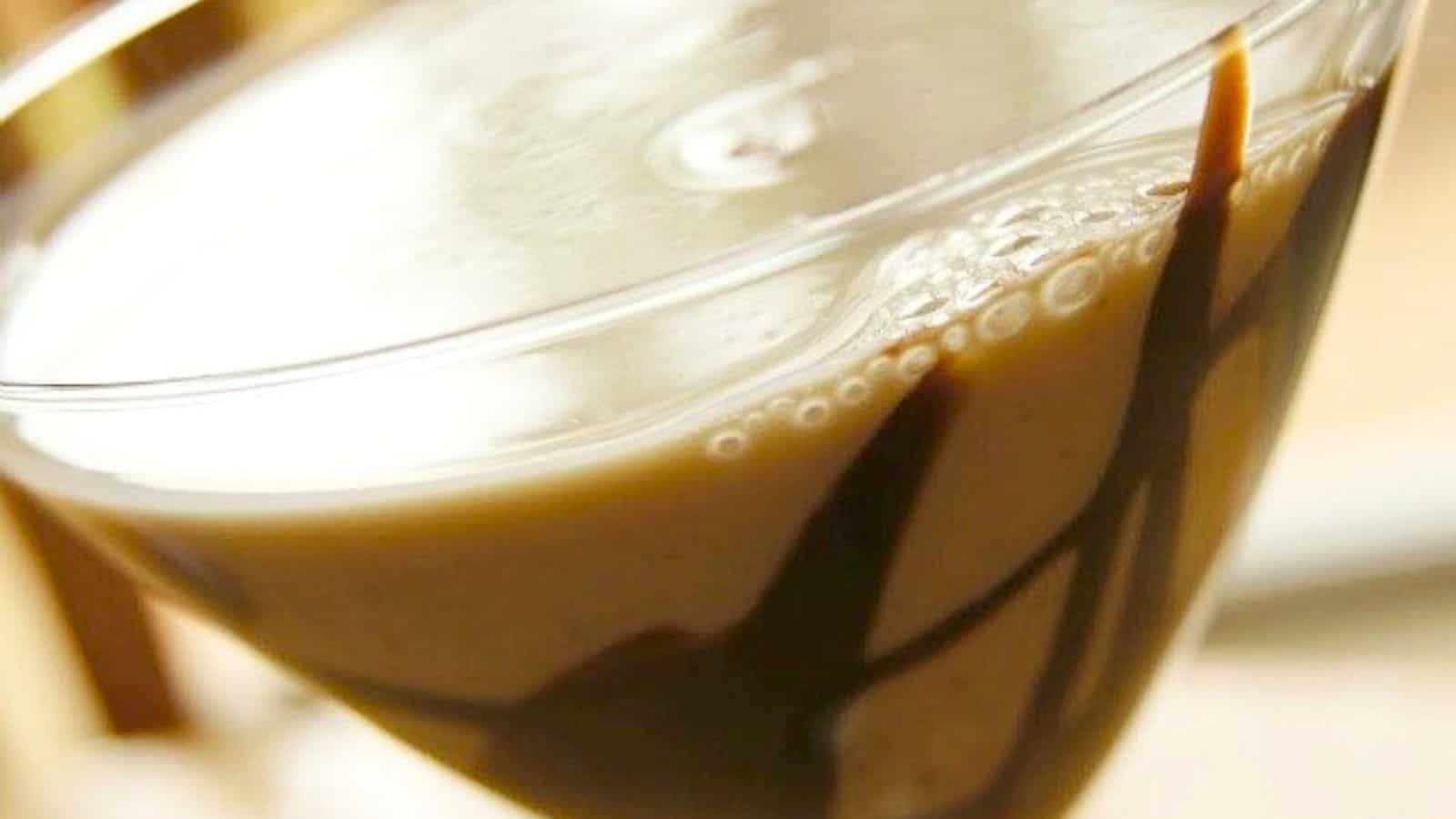 Image shows a chocolate martini in a glass with chocolate sauce design on the glass.