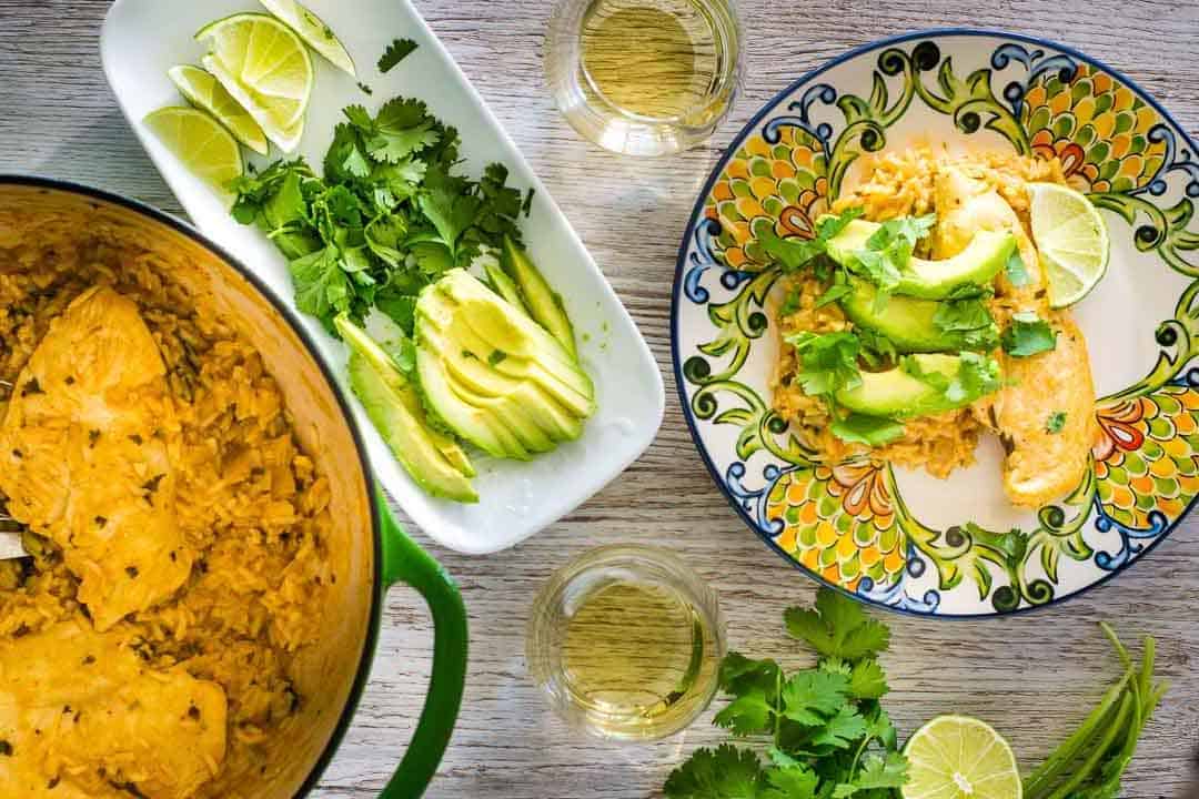 Cilantro lime chicken on a plate next to avocado and cilantro garnish.