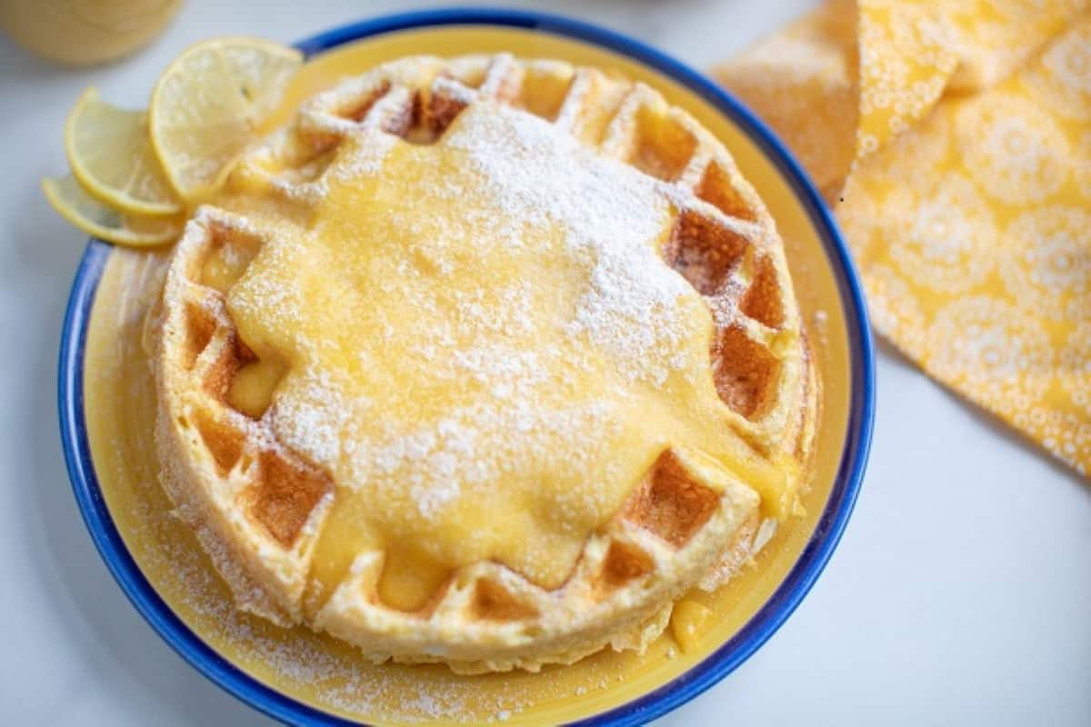 Lemon waffles with powdered sugar on a blue plate.