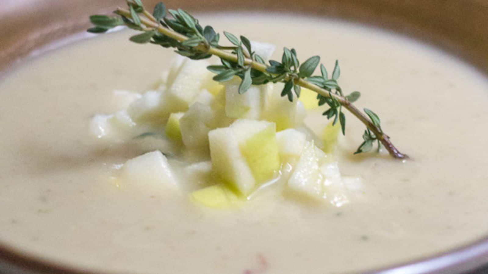 A bowl of soup with a sprig of thyme.