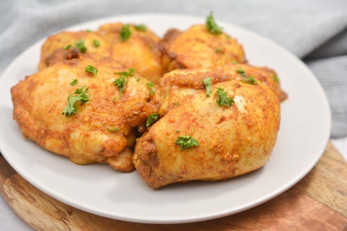 Chicken thighs on a white plate with parsley.