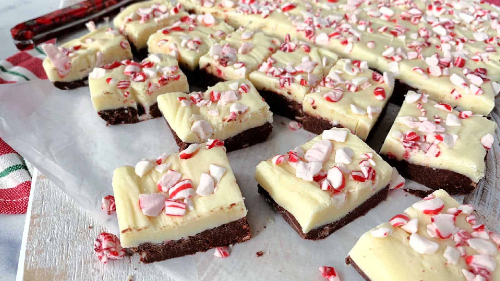 Two layer mint fudge on a piece of parchment paper on a white board.