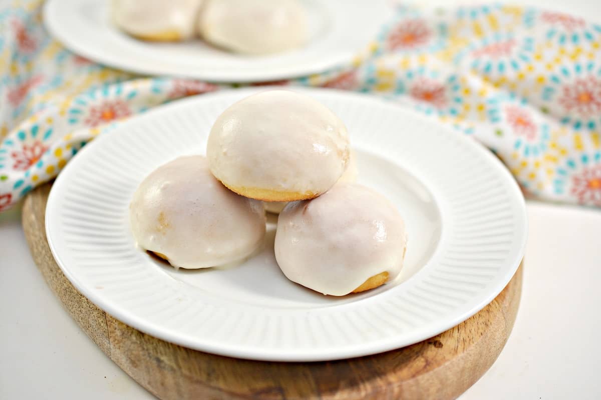 Three glazed donuts on a white plate.