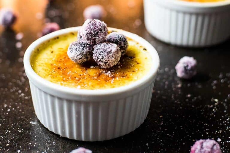 A bowl of creme brulee with berries on top.