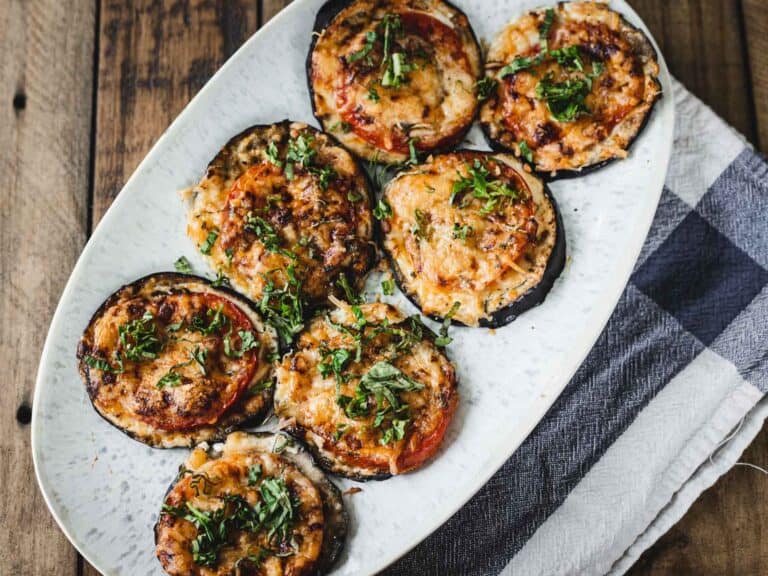 Eggplant stuffed with cheese and herbs on a white plate.