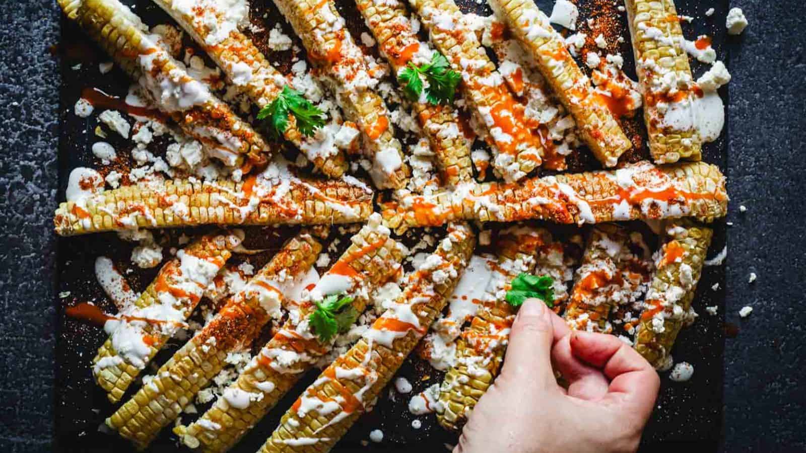 A person holding a tray of corn on the cob.