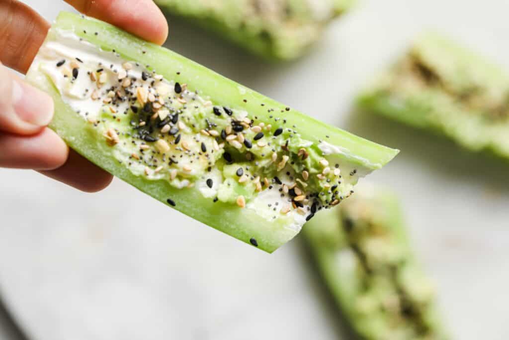 An everything bagel seasoning cucumber boat being held.