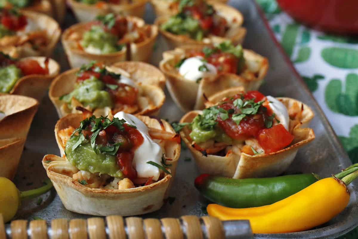 Mini chicken taco cups on a silver tray.