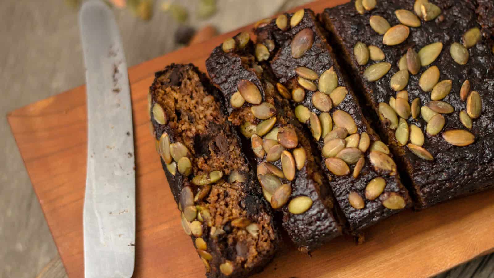 A slice of chocolate pumpkin bread on a cutting board with a knife.