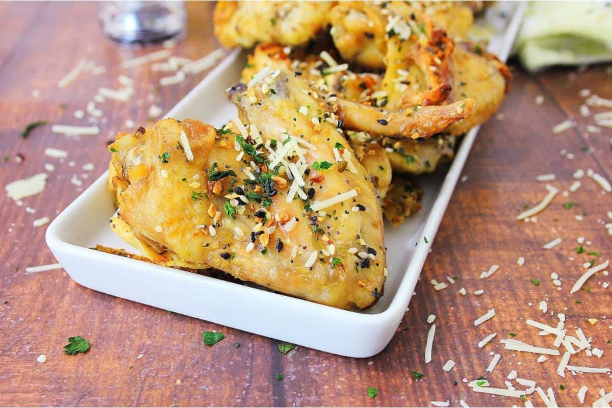 Chicken wings with parmesan and parsley on a white plate.