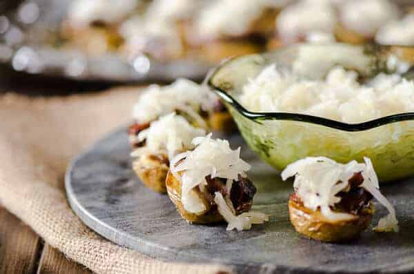 German cheesy potato bites on a plate with a bowl of sauerkraut.