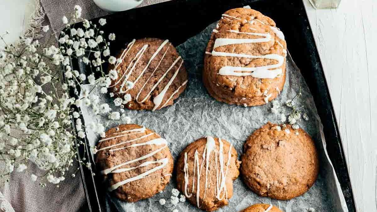 Butter pecan cookies on a tray drizzled with white chocolate.