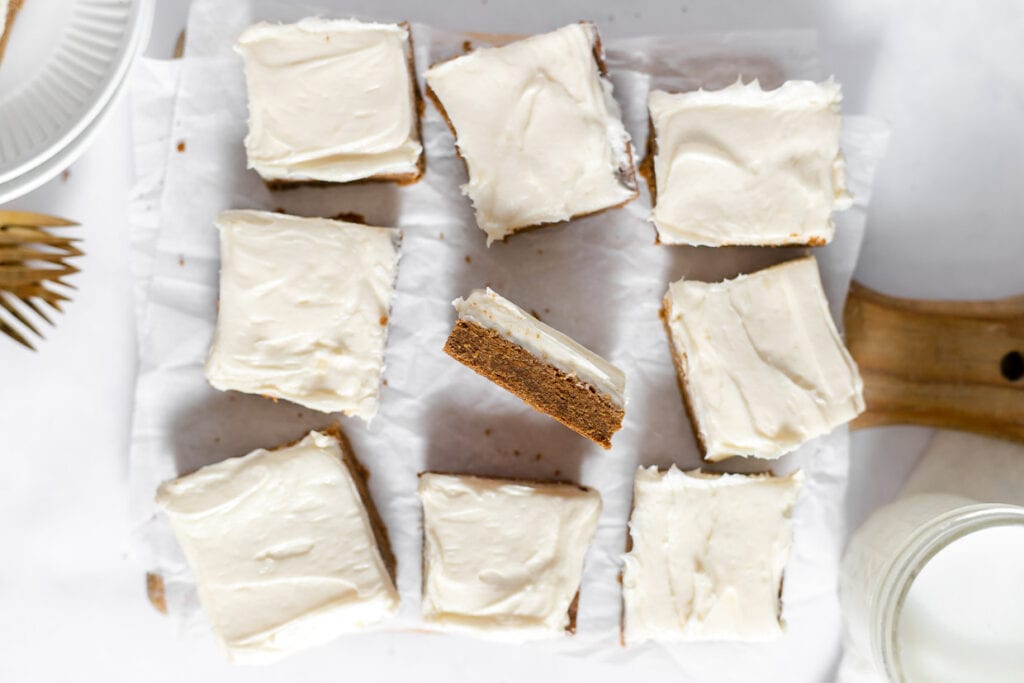 Gingerbread bars with cream cheese frosting on a cutting board.