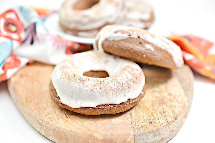 Two donuts on a wooden cutting board.