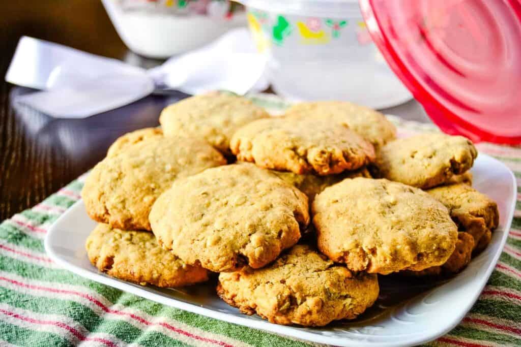 A plate of Christmas cookies on a table next to a bowl.