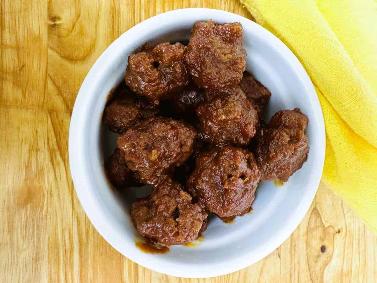 Meatballs in a white bowl on a wooden table.