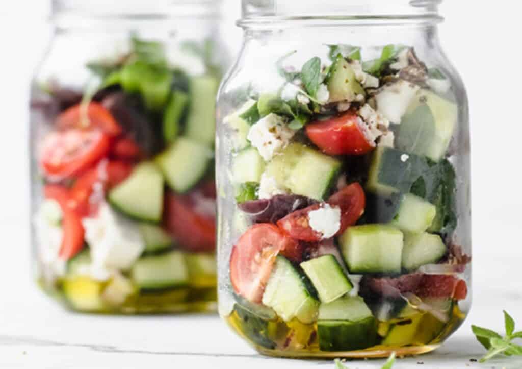 Two glass jars of Greek salad.