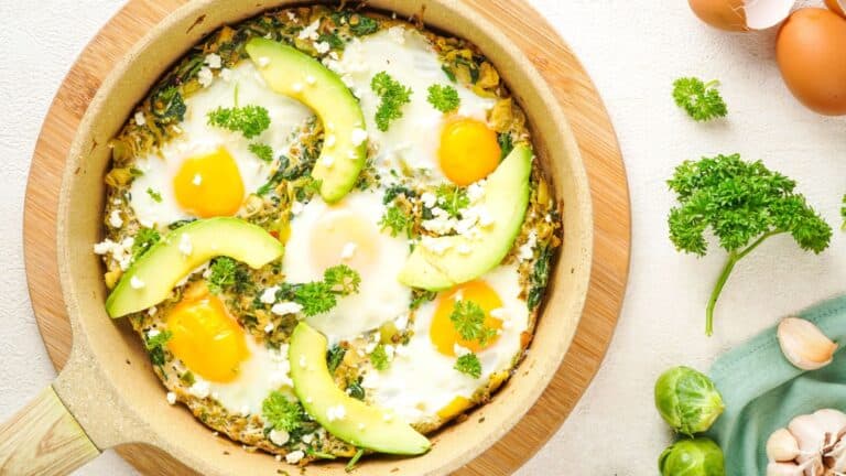 Skillet showing shakshuka with avocado garnish.