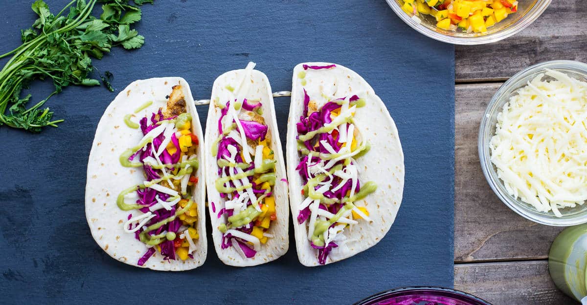 Grilled rockfish tacos assembled on a blue board.