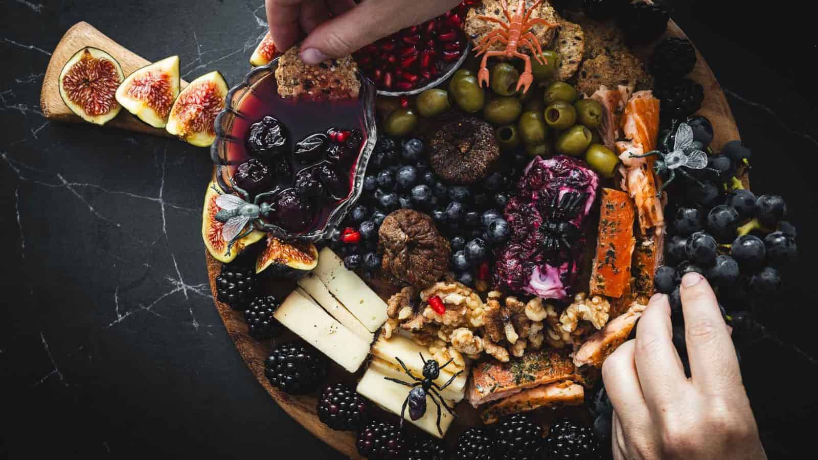 A person is holding a platter of cheese and fruit.