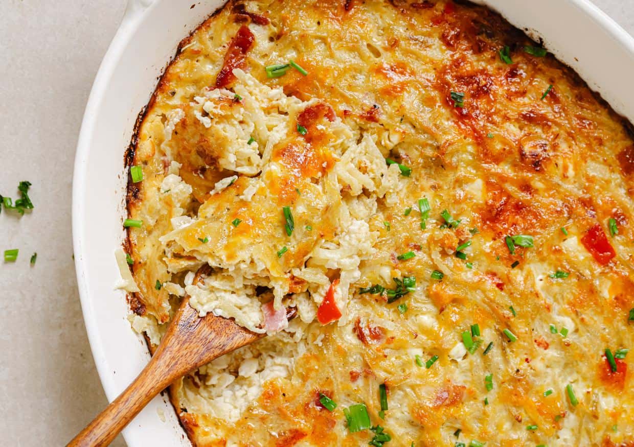 Hash brown breakfast casserole with a wooden spoon in it.