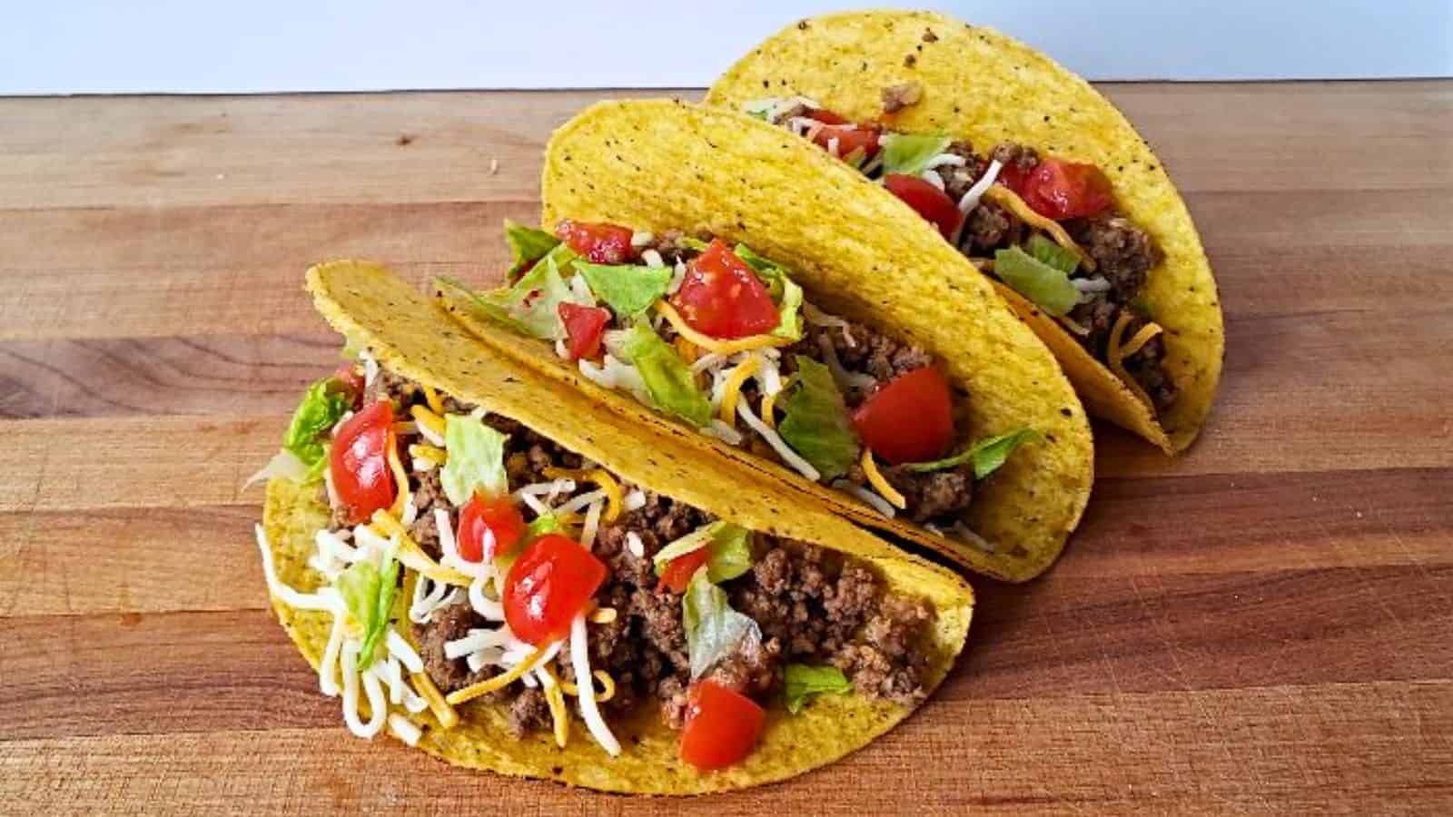 Image shows three honey habanero tacos with corn shells sitting on a wooden board.